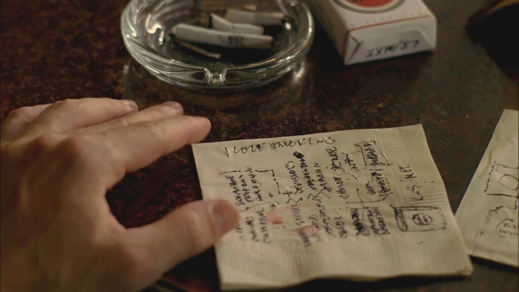 Screenshot from Mad Men, S1E1 depicting Don Draper writing on a napkin. | Source: kissthemgoodbye.net